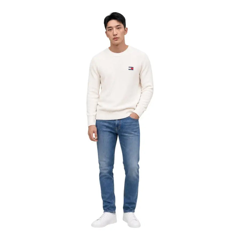 Un pull Tommy Hilfiger couleur crème en coton biologique, à col rond, avec un petit logo brodé sur la poitrine gauche.
