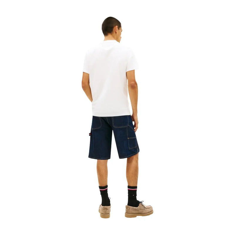 Short cargo en denim bleu foncé avec coutures renforcées et poches latérales, porté avec un t-shirt blanc en coton bio Tommy Hilfiger pour homme.