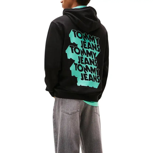 Au dos du sweat-shirt à capuche Tommy Hilfiger pour homme, en coton biologique noir, avec logo Tommy Jeans superposé turquoise et noir.