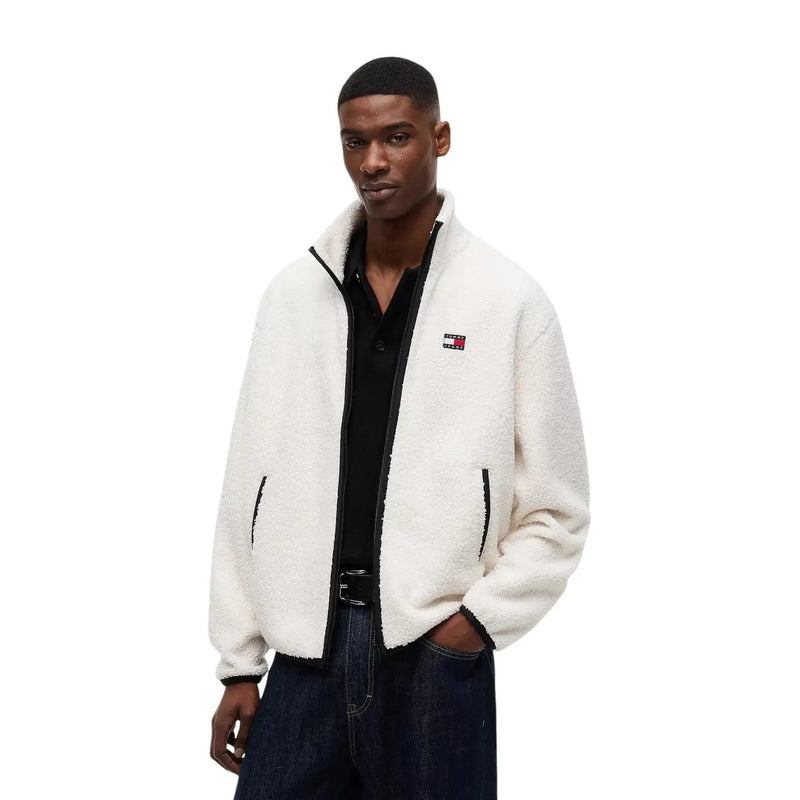 Veste polaire blanche duveteuse en polyester, avec fermeture éclair et finitions noires, ornée du logo Tommy Hilfiger sur la poitrine gauche.