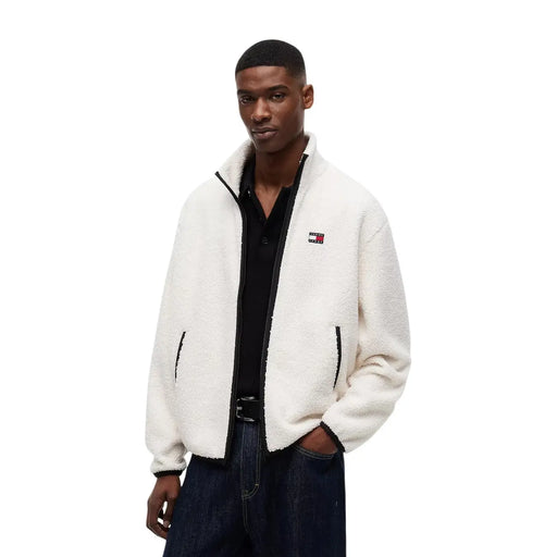 Veste polaire blanche duveteuse en polyester, avec fermeture éclair et finitions noires, ornée du logo Tommy Hilfiger sur la poitrine gauche.