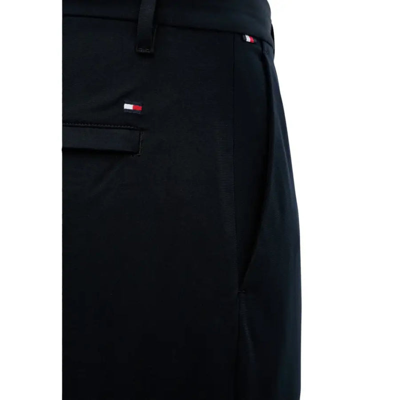 Pantalon noir Tommy Hilfiger pour homme, en tissu texturé discret, orné du logo rouge, blanc et bleu emblématique sur la ceinture et la poche.