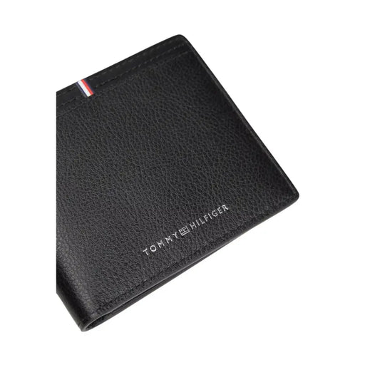 Tommy Hilfiger Portefeuille homme en cuir noir texturé avec logo argenté et languette à rayures rouges, blanches et bleues visible sur le devant