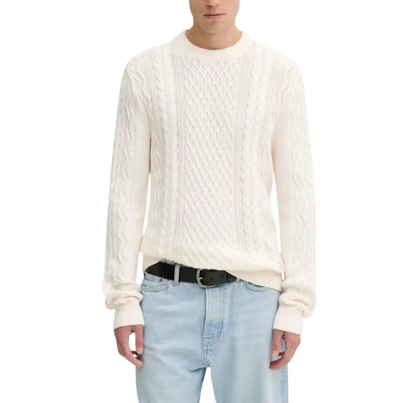 Cream cable knit sweater with black belt and light blue jeans.