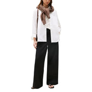 A woman wearing Tommy Hilfiger women black organic cotton wide-leg trousers with a white shirt and brown knitted scarf