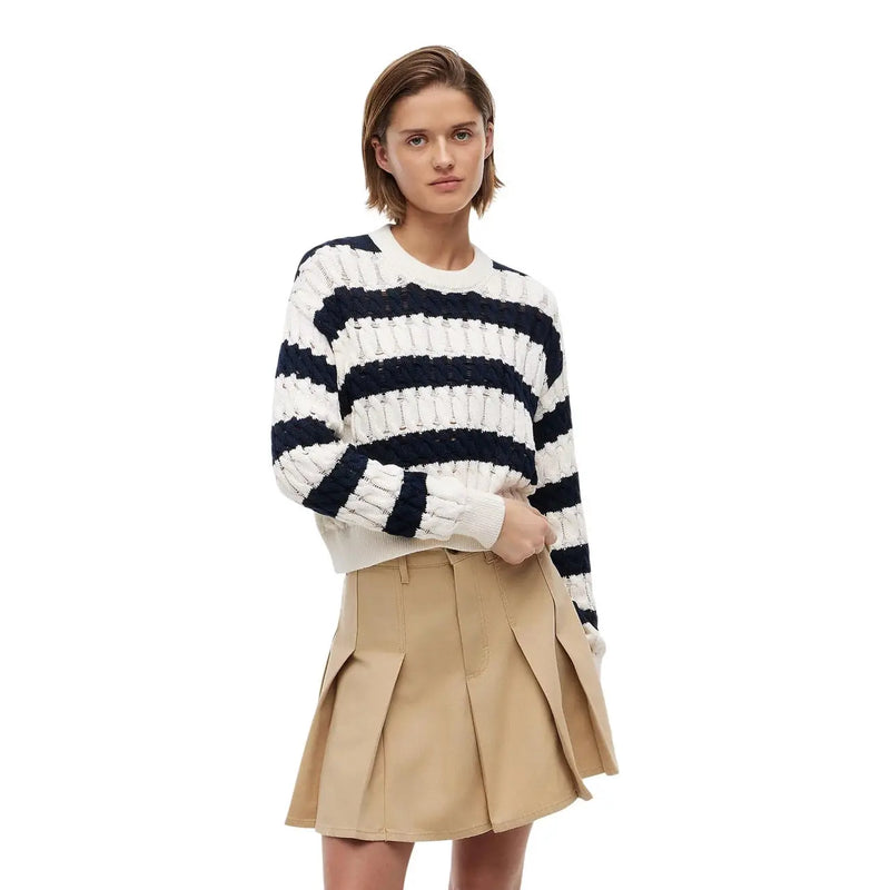 Une femme portant un pull en maille côtelée à rayures bleu marine et blanches en coton biologique bleu par Tommy Hilfiger