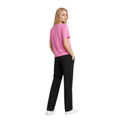 A woman wears a vibrant fuchsia Tommy Hilfiger organic cotton short-sleeved t shirt with black trousers