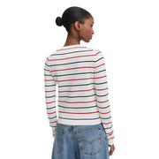Une femme porte un pull Tommy Hilfiger pour femme, blanc, en maille de coton biologique, à manches longues et col rond, orné de rayures.
