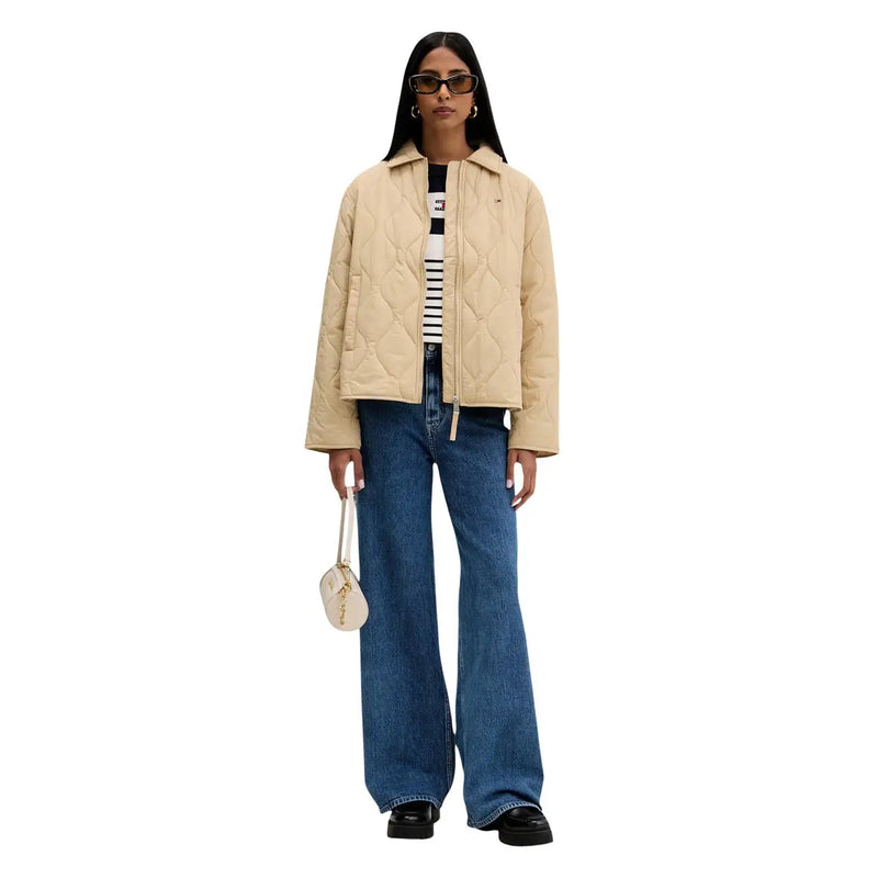 Veste matelassée beige à col classique et fermeture éclair sur le devant, portée avec un jean large en coton bleu clair Tommy Hilfiger pour femme