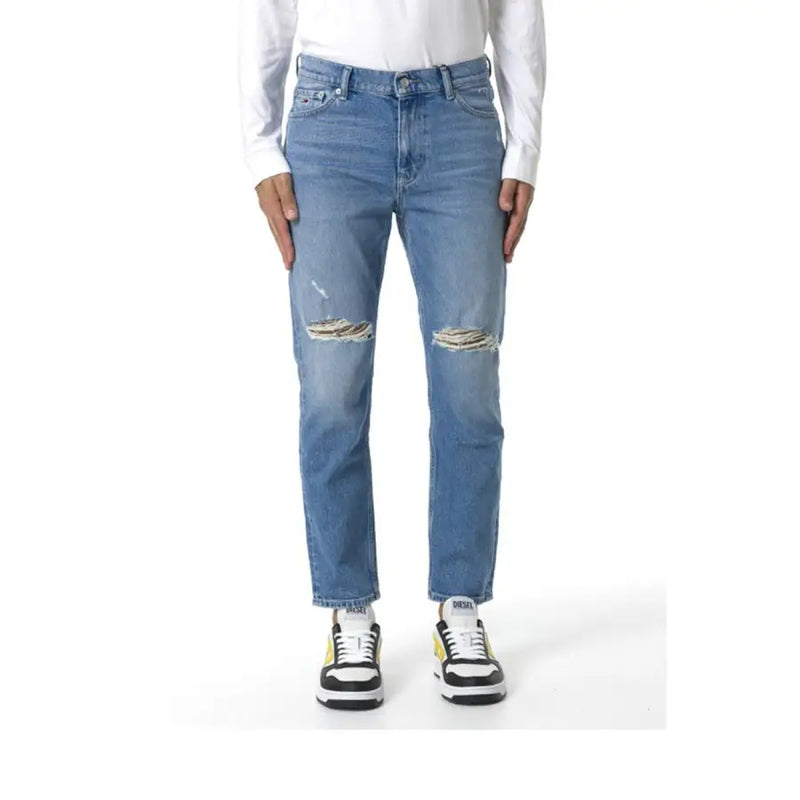 Blue distressed boyfriend jeans with white stitching and black sneakers.