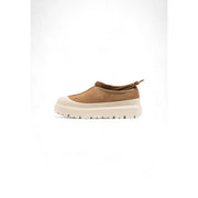 Pantoufles Ugg pour homme en daim beige, style slip-on, avec semelle en caoutchouc crème et bout texturé, idéales pour l'hiver.