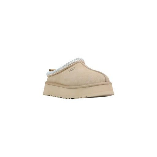 Pantoufles compensées en cuir beige UGG pour femmes, avec tige en daim et bordure tressée blanche, idéales pour le printemps.