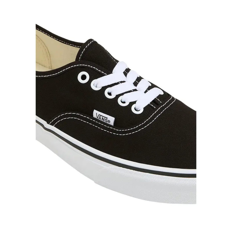 Baskets Vans pour homme, en tissu noir à lacets blancs, semelle en caoutchouc et surpiqûres blanches contrastantes.