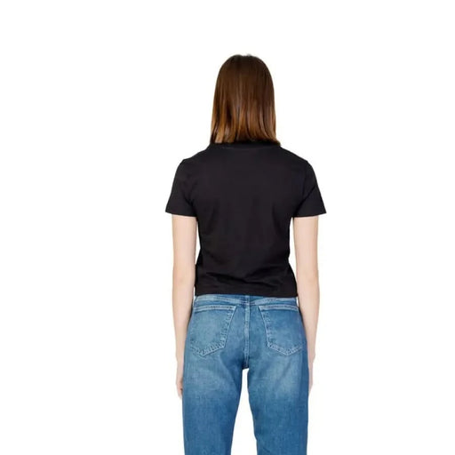 Back view of a woman in Calvin Klein Jeans black organic cotton t-shirt and blue jeans
