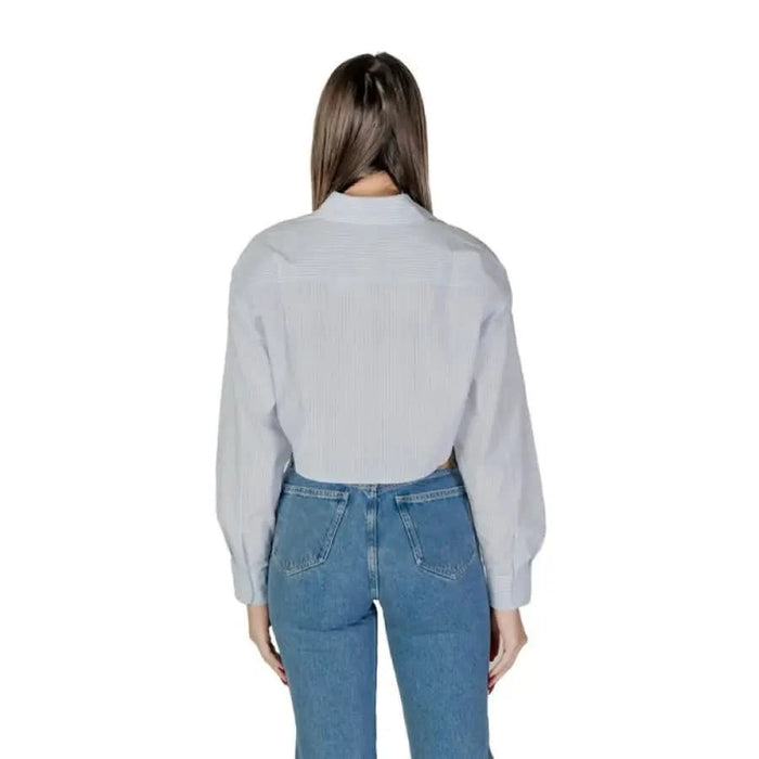 Back view of a woman in a white shirt and jeans featuring Calvin Klein Jeans design