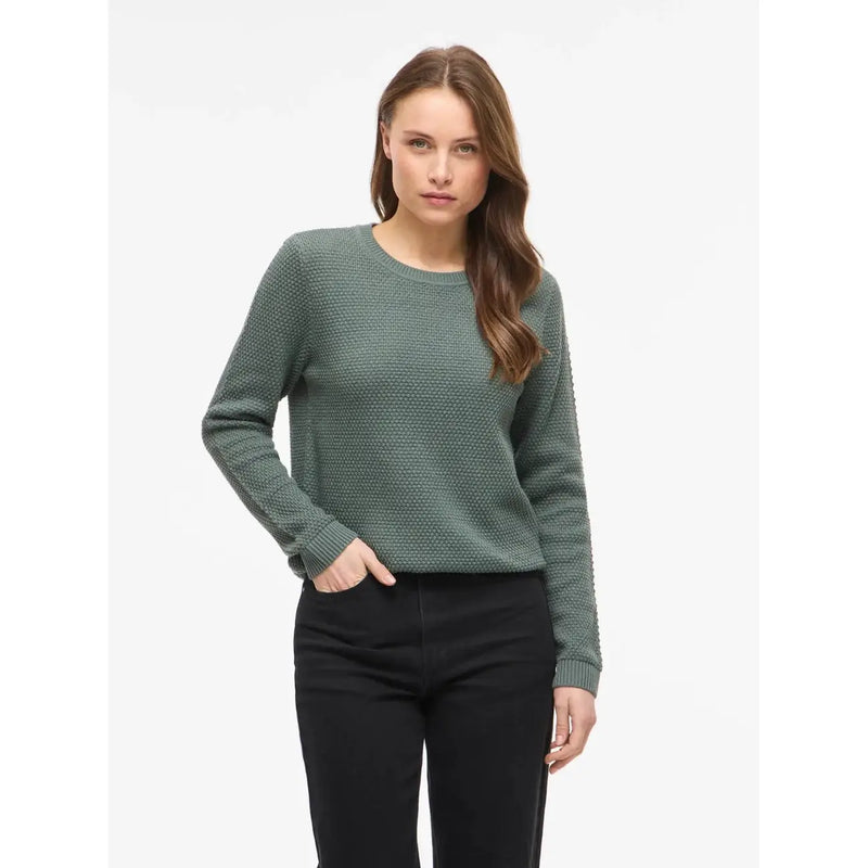 Pull long en maille de coton noir à col rond pour femme Vila, associé à un pull en maille texturée vert olive à poignets côtelés.
