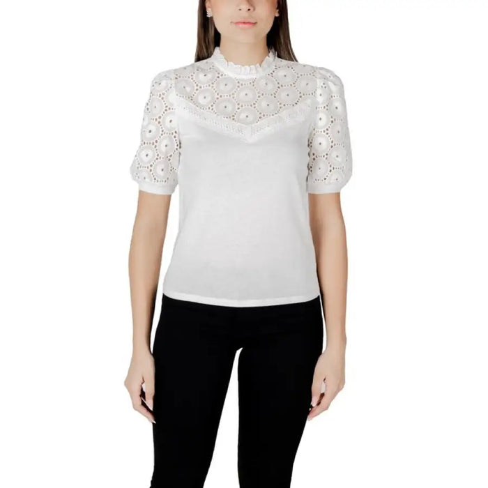 White blouse with eyelet detailing paired with black pants in a stylish women’s outfit