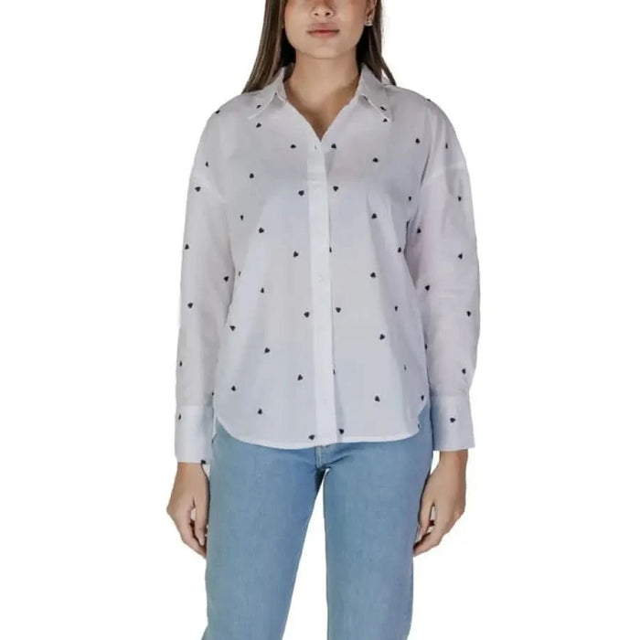 White button-up shirt with black polka dots and light blue jeans styled elegantly