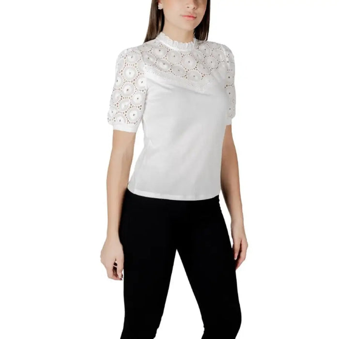 White lace-trimmed blouse paired with black pants for women in a fashionable outfit