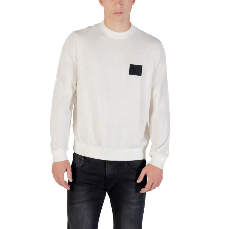 White long sleeved crewneck sweater featuring a black rectangular patch on the left chest in soft knit material