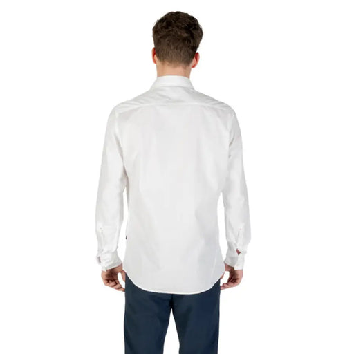 White long-sleeved button-down shirt paired with dark pants in a fashion product display