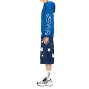 Person wearing blue paisley hoodie, denim skirt with star cut-outs, white socks, sneakers