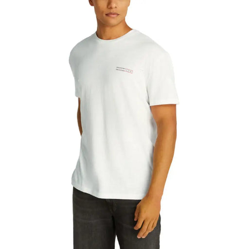T-shirt blanc à manches courtes présenté avec un t-shirt noir à col rond pour homme et un jean. Shorts