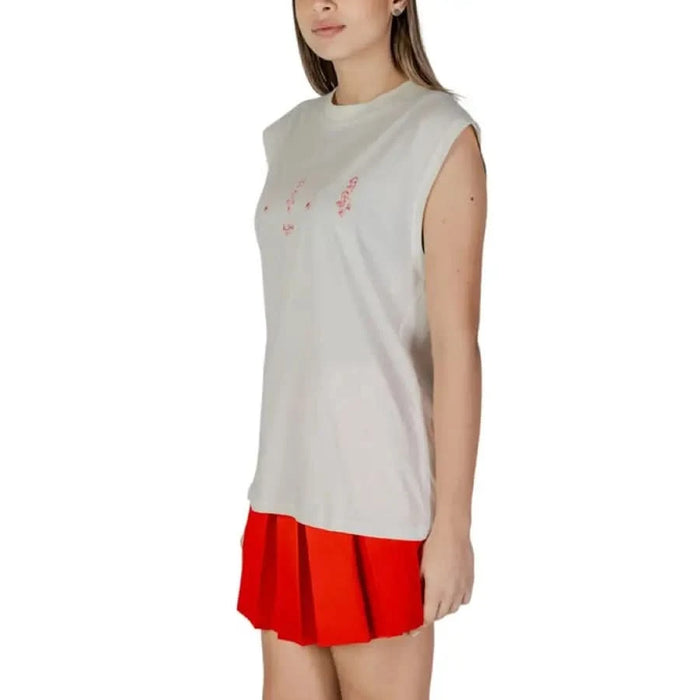 White sleeveless round neck tank top with pink text paired with red pleated skirt
