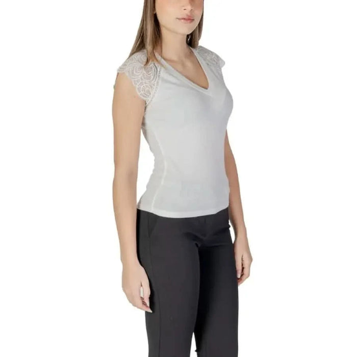 White V-neck top with lace cap sleeves paired with black pants by Morgan De Toi