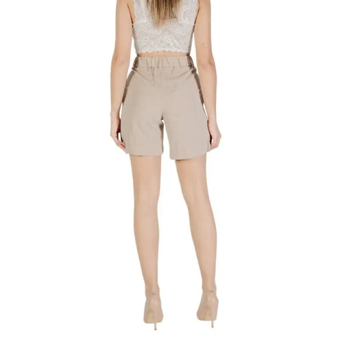 Woman wearing beige high-waisted shorts and heels for a stylish casual look