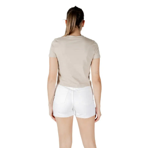 Woman wearing beige T shirt and white denim shorts in a casual summer outfit