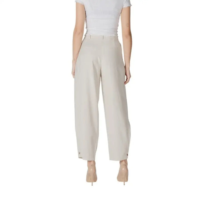 Woman showcasing stylish beige pleated trousers in wide-leg design
