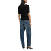 Woman wearing a black knit top with leaf pattern and blue jeans