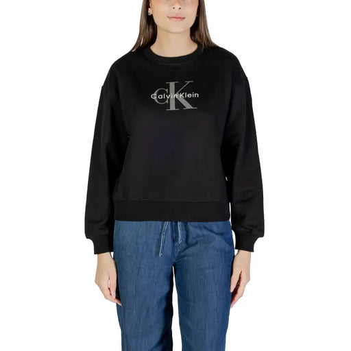 Woman wearing a black Calvin Klein long-sleeved sweatshirt and blue denim drawstring pants
