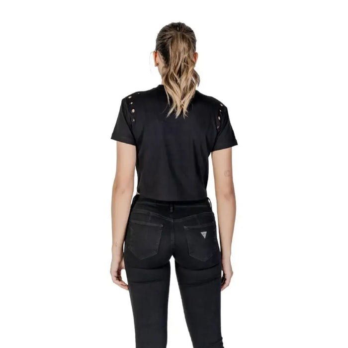 Woman wearing black crop top and jeans showcasing the Black Tie Front T Shirt with Grommets