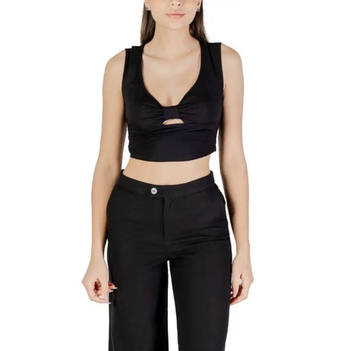 Woman wearing a black crop top and matching pants, styled elegantly for a modern look