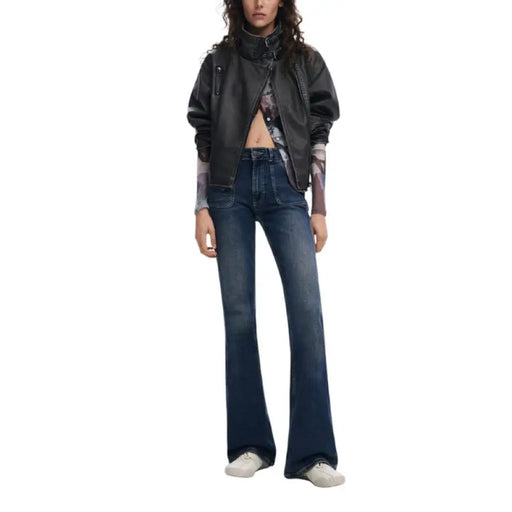 Woman wearing a black faux leather biker jacket and blue flared jeans