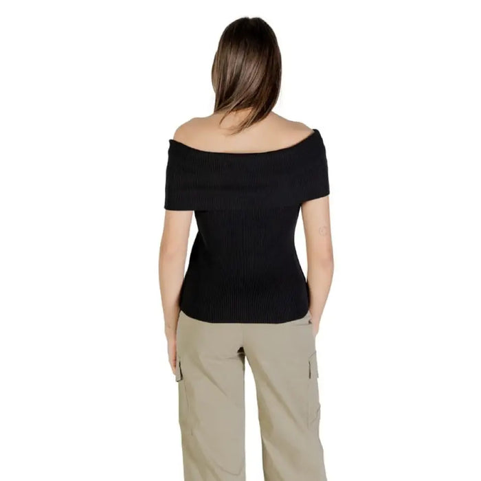 Woman wearing black off-the-shoulder ribbed top and khaki pants outfit display