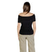 Woman wearing black off-the-shoulder ribbed top and khaki pants outfit display