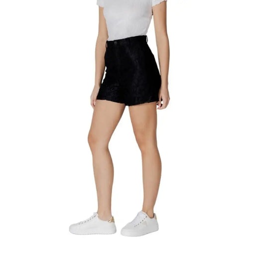 Woman wearing black high waisted mini skirt and white sneakers outdoors