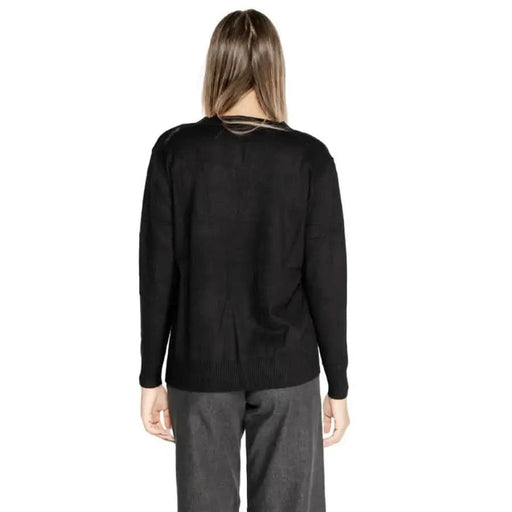Woman in black sweater and gray pants modeling Clerè Women’s Long Black V-Neck Knit Sweater