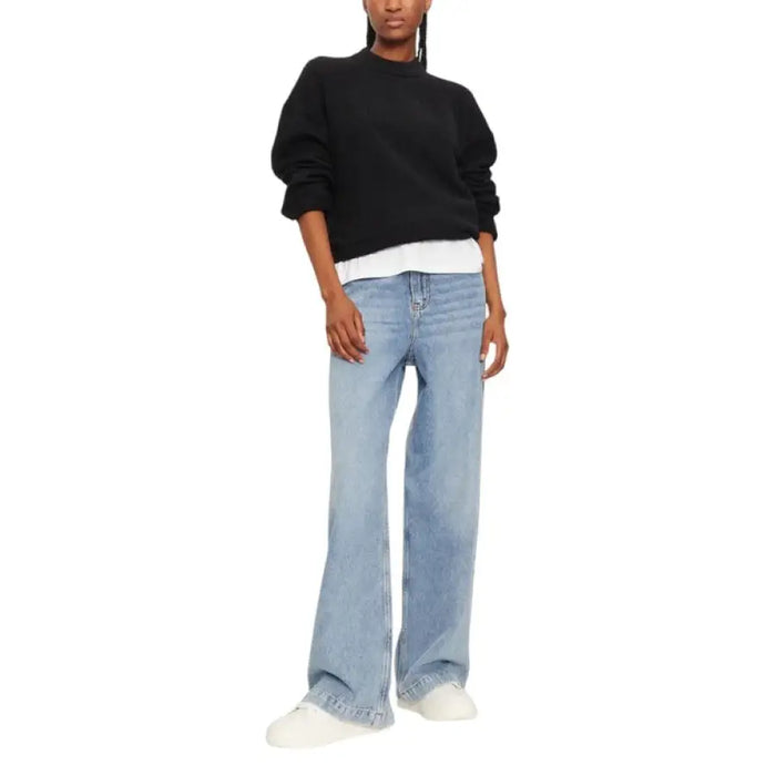Woman wearing black oversized knit sweater with wide-leg jeans for a casual look