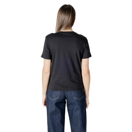 Woman wearing Calvin Klein Jeans black short sleeve round neck T shirt and dark blue jeans
