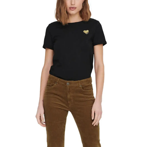 Woman wearing a black T-shirt and brown corduroy pants posing outdoors