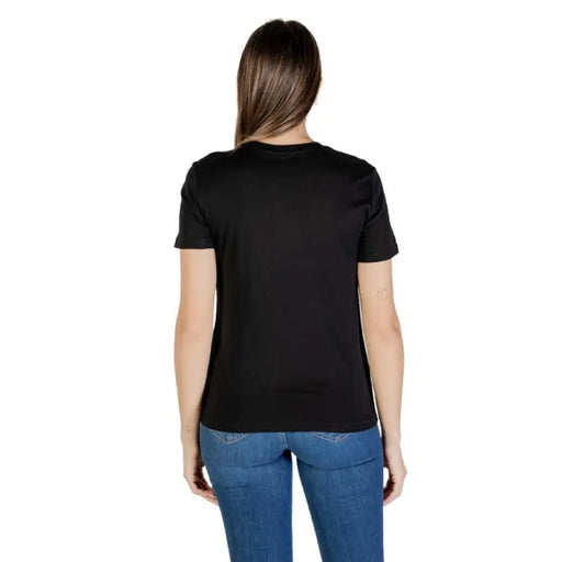 Woman wearing Black T Shirt with Decorated Pocket and blue jeans showcasing casual style