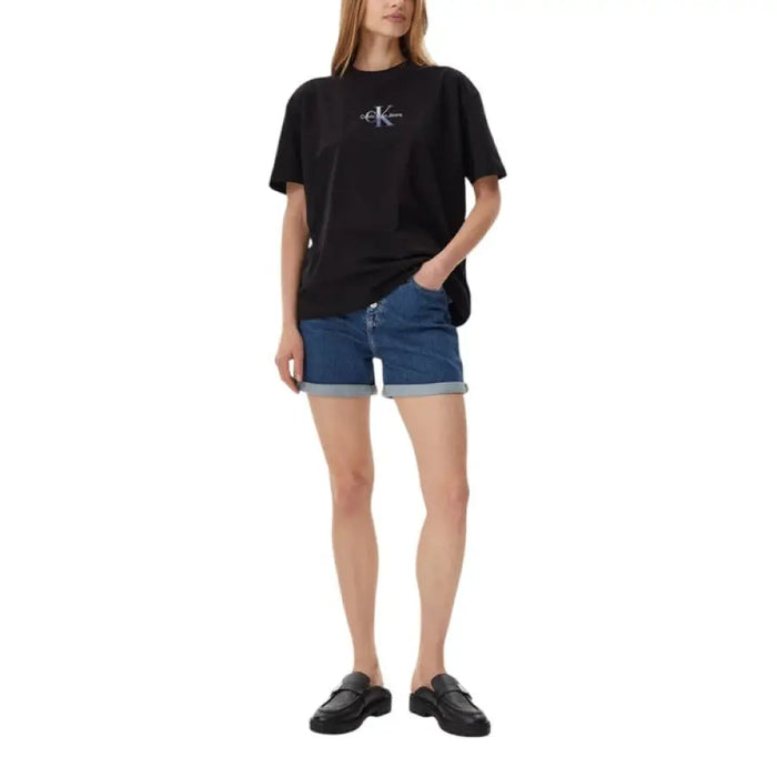 Woman wearing a black T-shirt and denim shorts in a casual setting