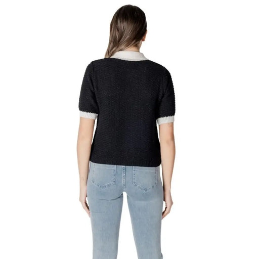 Woman wearing a black, white, and cream collared cardigan with jeans