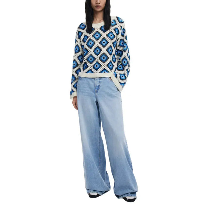 Woman wearing a blue and white crocheted sweater with wide-leg jeans fashion ensemble