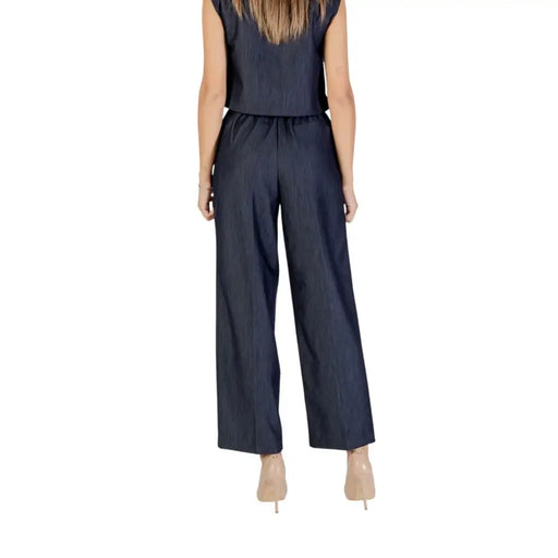 Woman wearing a dark blue pinstripe two-piece wide-leg jumpsuit with front pockets