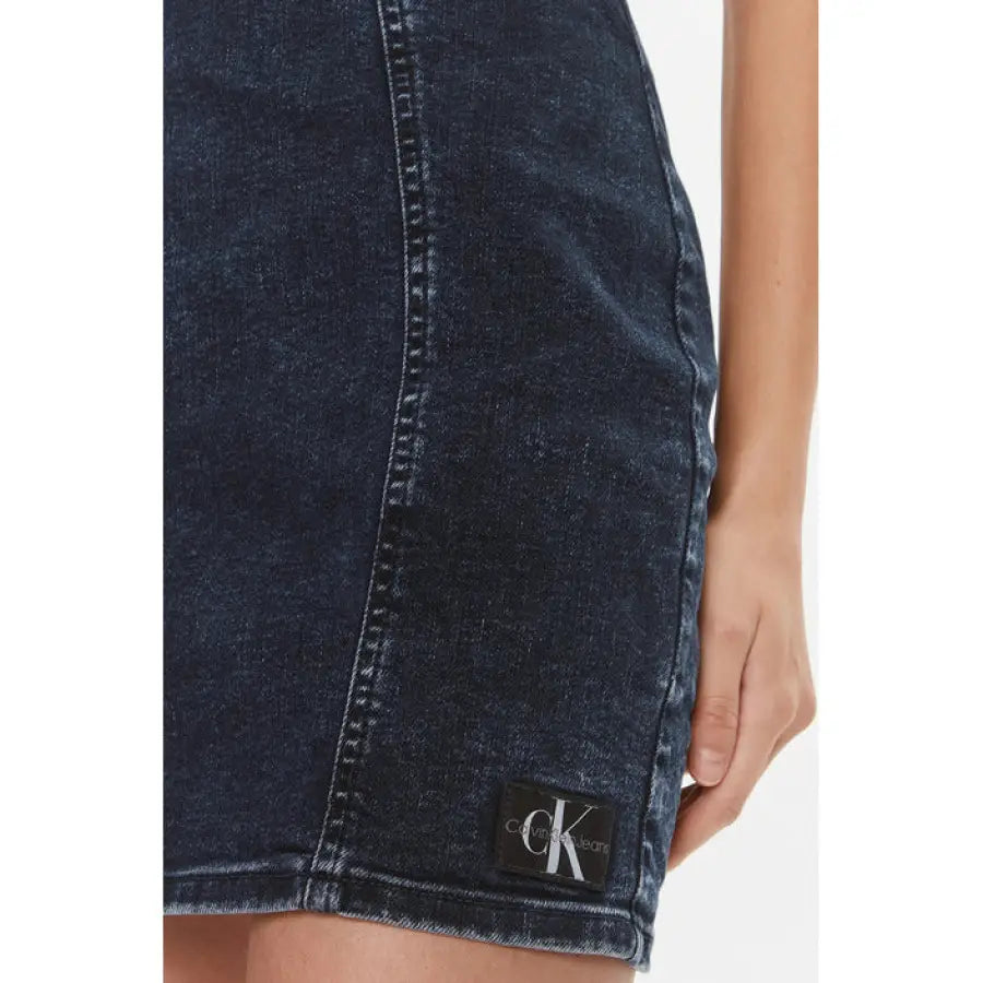 
                      
                        Calvin Klein woman in denim skirt and white t-shirt from Calvin Klein Jeans collection.
                      
                    